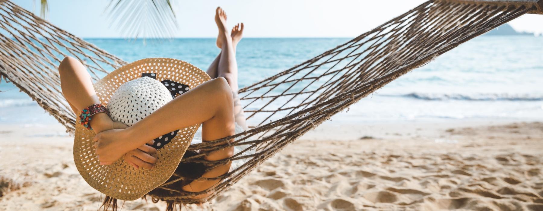 a person lying on a hammock on a beach